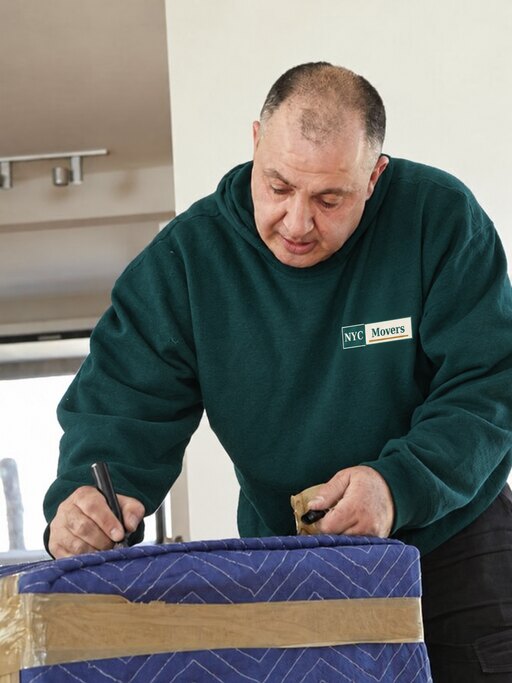 Mover carefully preparing and protecting wrapped furniture