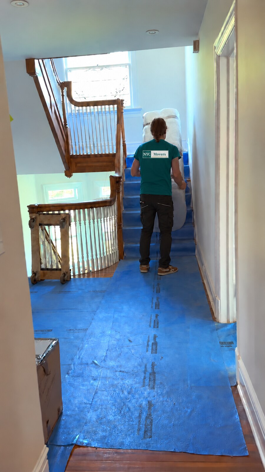 A mover guiding protected furniture along covered floors and stairs